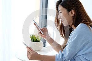 Young asian woman holding credit card and using smart phone for