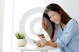 Young asian woman holding credit card and using smart phone for