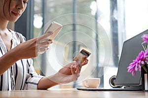 Young asian woman holding credit card and using tablet computer. Businesswoman working at home. Online shopping, e