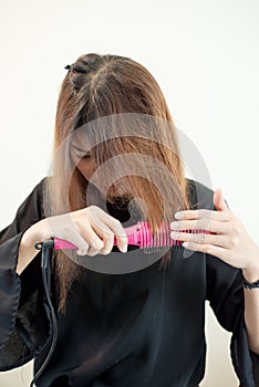 Young asian woman is holding Hair straighteners.