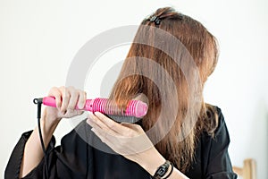 Young asian woman is holding Hair straighteners.