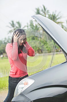 Young Asian woman holding her head, confuse because her car trouble