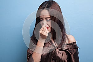 Young Asian woman holding her nose because of a bad smell.