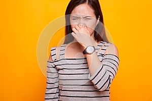 Young Asian woman holding her nose because of a bad smell.