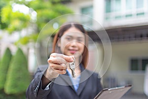 Young asian woman holding the key with new house. Real Estate Agent giving house keys