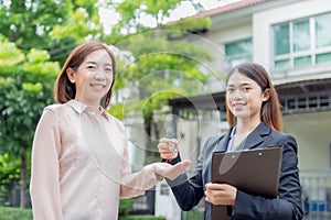 Young asian woman holding the key with new house. Real Estate Agent giving house keys