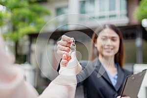 Young asian woman holding the key with new house. Real Estate Agent giving house keys