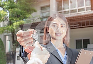 Young asian woman holding the key with new house. Real Estate Agent giving house keys