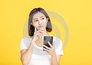 Young asian woman holding mobile phone and looking away