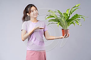 Young asian woman  holding a pots on grey background