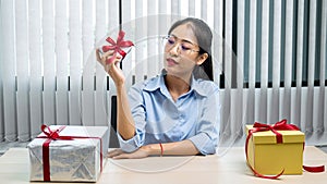 Young asian woman holding a small silver gift box to preparing celebration
