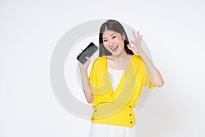 Young asian woman holding smartphone and shows OK sign on white background