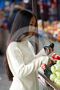 Young asian woman holding vegetables at market