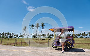 A young asian woman holding watermelon next to the sidecar while traveling in countryside