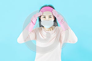 Young Asian Woman housewife in pink t-shirt wore face mask ,have an ache and fatigued isolated on blue background,housework and