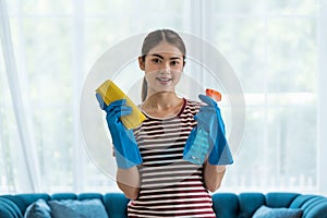 Young Asian woman housewife wearing gloves cleaning glass with microfiber cloth and spray disinfectant