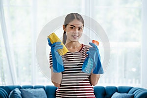 Young Asian woman housewife wearing gloves cleaning glass with microfiber cloth and spray disinfectant
