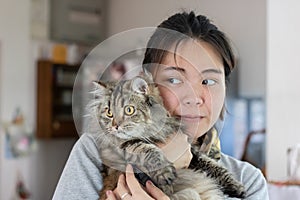 Young Asian woman is hugging a persian cat with indoor scene