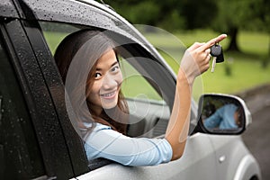 Young asian woman inside a car, hold the key out from the window