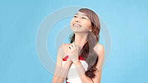 Young asian woman isolated on blue background has friendly expression  pressing palm to chest. Love concept