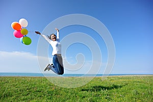 Young asian woman jumping with colored balloons