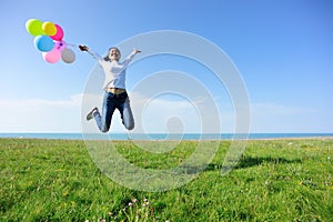 Young asian woman jumping with colored balloons