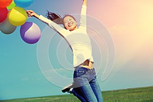 Young asian woman jumping with colored balloons