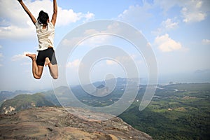 Young asian woman jumping on mountain peak rock