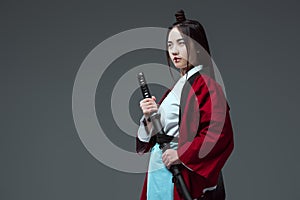 young asian woman in kimono holding katana and looking away