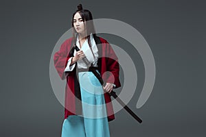 young asian woman in kimono holding katana sword and looking at camera