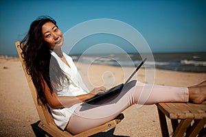 Young Asian Woman with Laptop computer during tropical beach vacation