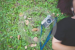 Young Asian woman laying on the green grass listening to music in the park with a chill emotion.