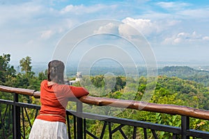 Young Asian woman leaning on railing at scenic lookout