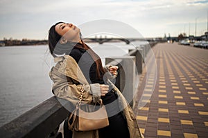 Young asian woman lifestyle with winter clothing along a seawall on the bay with a downtown skyline.