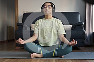 Young asian woman listening relaxing music and meditating doing the easy pose.