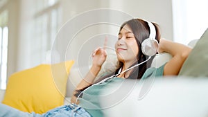 Young asian woman listening to music on couch in living room at home