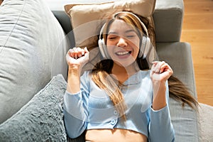 Young asian woman listening to music on couch in living room at home