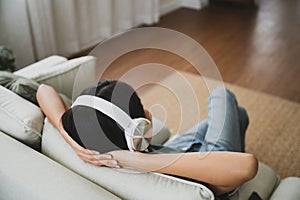 Young asian woman listening to music on couch in living room at home