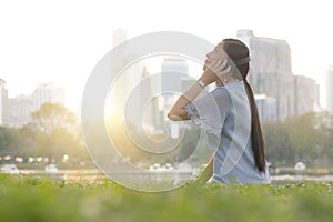 Young Asian woman is listening to music by wearing wireless headphone and taking smartphone