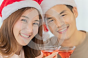 Young asian woman with long brown hair wearing red and white santa hat and pink sleeveless dress celebrating and cheering with her