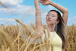 Young Asian woman with long hair relaxes in a wheat field