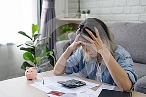 Young Asian woman looking at credit card invoice in her hands and worry about cash on bills payday. Business financial concept