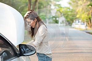 Young Asian woman looking at her broken down car