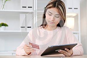 Young asian woman make payment online shopping by credit card via digital tablet