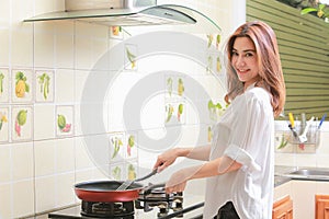 Young asian woman making omelette in a kitchen.