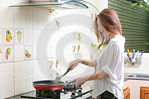 Young asian woman making omelette in a kitchen.