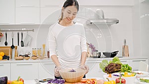 Young Asian woman making salad healthy food in the kitchen, beautiful female in casual use organic vegetables lots of nutrition