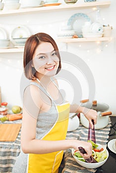 Young asian woman making salad in kitchen smiling and laughing h