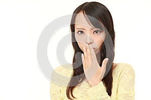 Young Asian woman making the speak no evil gesture