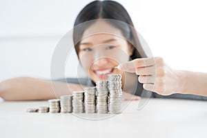 Young Asian woman making stack of coins. invest save finance concept.